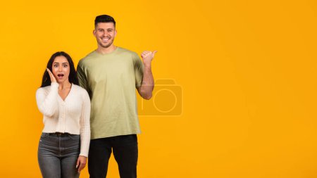 Téléchargez les photos : Smiling shocked millennial arabic woman with open mouth and man pointing finger to copy space, recommends ad and offer, isolated on orange background, studio. Advice, win and huge sale, good news - en image libre de droit