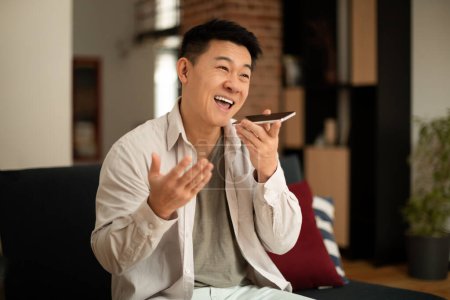 Photo for Portrait of happy asian man holding cellphone near mouth and recording message, using mobile voice recognition or digital assistance app speaking with virtual assistant - Royalty Free Image