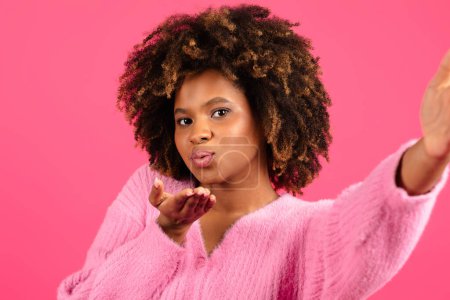 Photo for Cheerful young black curly lady in casual taking selfie, blowing kiss at camera isolated on pink background, close up, studio. Photo for blog and social networks, blogger shooting video, offer and ad - Royalty Free Image