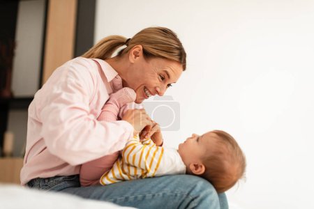 Téléchargez les photos : Lovely happy woman cuddling with her adorable baby girl, playing and having fun, mother njoying child care during maternity leave, home interior, copy space - en image libre de droit