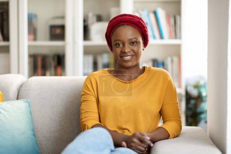 Foto de Young calm black woman wearing casual outfit relaxing on comfortable sofa in modern living room, lazy happy african american woman resting on couch, enjoy peace of mind no stress at home, copy space - Imagen libre de derechos