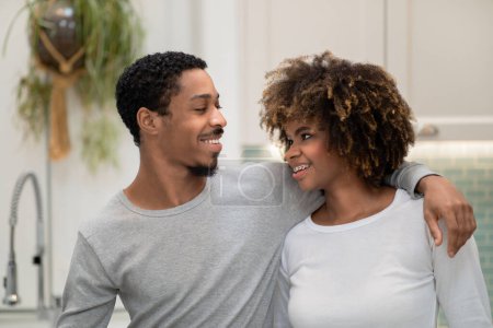 Téléchargez les photos : Happy Marriage, Relationships. Handsome african american husband hugging pretty curly wife, looking at her and smiling, standing at home, young couple embracing posing together at kitchen - en image libre de droit