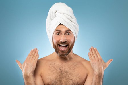 Téléchargez les photos : Morning shower and beauty routine. Funny middle aged caucasian bearded man posing with towel on head on blue background, studio shot - en image libre de droit