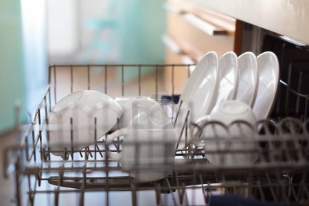 Photo for Closeup Shot Of Open Built-in Dishwasher Machine With Clean Dishes And Cups After Washing, Modern Kitchen With Integrated Appliances, Technology For Housekeeping Concept, Selective Focus - Royalty Free Image