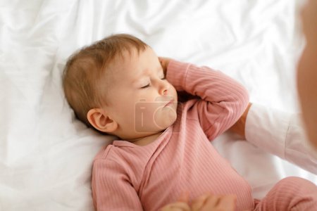 Foto de Daysleep concept. Closeup shot of cute little baby girl sleeping in bed, child lying with closed eyes on white linens, above view. Adorable infant kid napping at home - Imagen libre de derechos