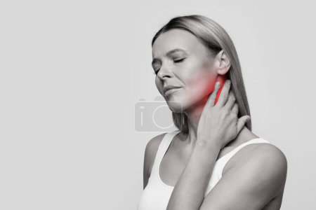 Photo for Unhappy middle aged woman feeling exhausted and suffering from neck pain, touching inflamed red zone, isolated on studio background, black and white panorama photo, empty space - Royalty Free Image