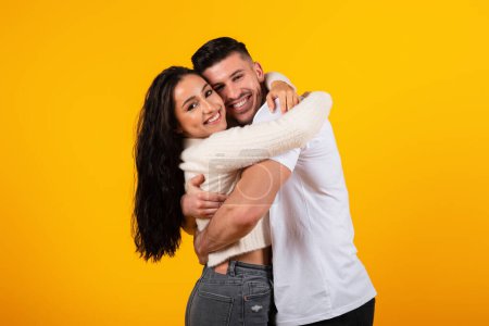 Foto de Glad young arabic husband hugging wife at date, enjoy tender moment, look at camera isolated on yellow background, studio. Meeting, family relationship, love and romantic, lifestyle, ad and offer - Imagen libre de derechos