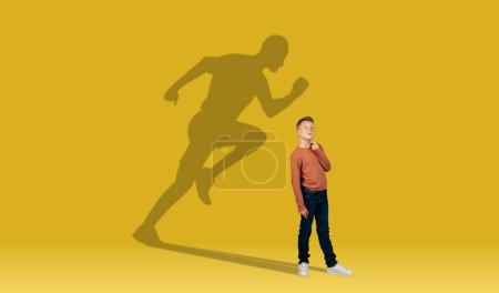 Photo for Childhood and dream about big and famous future. Conceptual image with boy and drawned shadow of sportive athletic male runner behind on yellow background. Copy space for ad, text, collage - Royalty Free Image