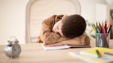 Photo for Bored unhappy tired caucasian little child sleeping at table, suffering from homework in room interior. Problems in study, education at school kindergarten and home, childhood and lesson and overwork - Royalty Free Image