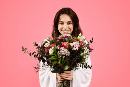 Foto de Cheerful pretty young european lady enjoy gift, bouquet of white tulips, spring holiday, isolated on pink background, studio. Congratulation with women day, birthday, romantic date and anniversary - Imagen libre de derechos