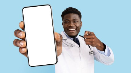 Photo for African American Male Doctor In Uniform Pointing At Smartphone With Blank Screen In His Hand, Positive Black Physician Man With Stethoscope Recommending Mobile App Or Website, Collage, Mockup - Royalty Free Image