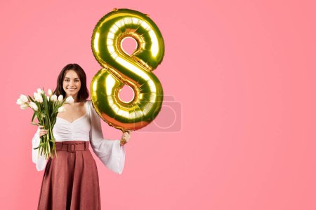 Téléchargez les photos : Smiling young european lady hold bouquet of flowers, balloon number 8, enjoy spring holiday, isolated on pink background, studio. Gift, congratulation and celebration, birthday greeting, ad and offer - en image libre de droit