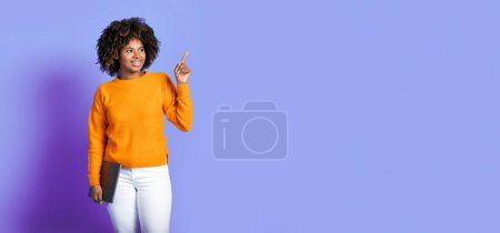Photo for Happy attractive bright young african american woman in stylish outfit digital nomad with modern laptop pointing at copy space over purple studio background, showing job seeking website or app, banner - Royalty Free Image
