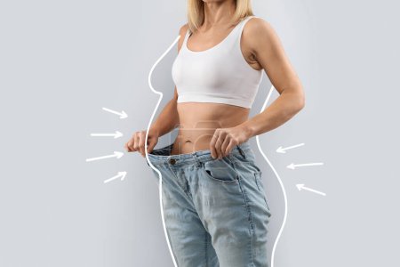 Téléchargez les photos : Recadrée d'une jolie femme mince portant un énorme jean, montrant les résultats du régime alimentaire, lignes de forme de corps blanc autour de dame mince méconnaissable, collage pour le concept minceur, espace de copie - en image libre de droit
