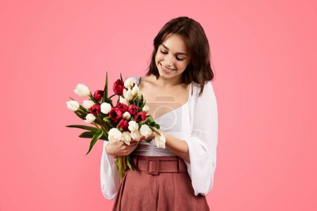 Téléchargez les photos : Smiling young european female with bouquet of flowers, enjoy lifestyle, present, rejoice spring festival isolated on pink background, studio. Holiday gift, congratulated with birthday, ad and offer - en image libre de droit