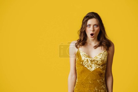 Foto de Omg. Retrato de la señora sorprendida abriendo la boca en la emoción, mirando a la cámara con asombro, de pie sobre el fondo amarillo del estudio, espacio de copia - Imagen libre de derechos