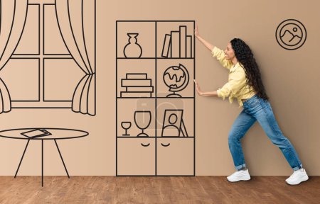 Photo for Excited young middle eastern lady in casual outfit moving imaginary cabinet on interior sketch, happy millennial woman posing at new apartment, full length shot, collage. Real estate concept - Royalty Free Image