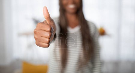 Photo for Unrecognizable black woman with long dreadlocks in casual outfit showing thumb up, aftican american lady recommending something nice, home interior, panorama, copy space - Royalty Free Image