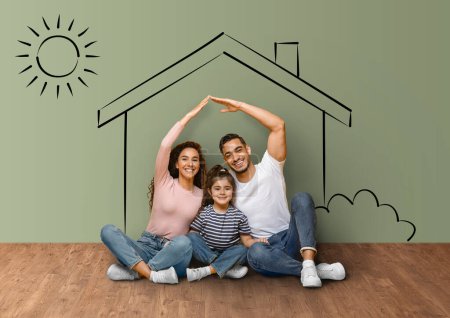 Téléchargez les photos : Positive muslim family enjoying their new apartment, happy young father and mother imitating roof over their cute little daughter head, house sketch background, collage. Mortgage concept - en image libre de droit