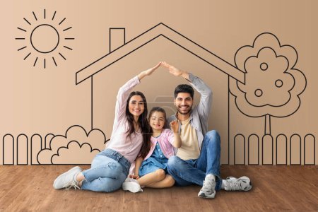 Foto de Mortgage for young families, collage. Happy middle eastern family moving to their own home. Parents joining hands making symbolic house roof, sitting together over house sketch background - Imagen libre de derechos