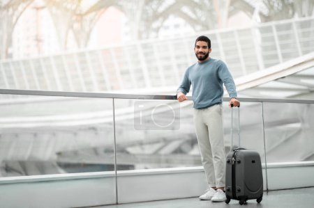 Photo for Happy Tourist Man Posing With Travel Suitcase Smiling Looking At Camera Standing At Modern Airport. Transportation And Cheap Tickets Offer Concept. Full Length Shot, Empty Space For Text - Royalty Free Image