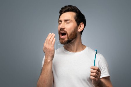 Téléchargez les photos : Middle aged man holding hand near mouth and checking breath freshness, worrying about poor oral hygiene, suffering from unpleasant odor, standing over grey background - en image libre de droit