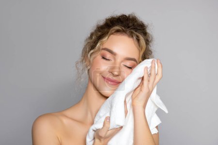 Photo for Woman cleaning facial skin with towel after washing face, beautiful lady wiping facial skin with soft towel, removing makeup, standing over grey background - Royalty Free Image
