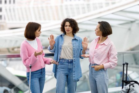Portrait Of Three Young Females Arguing At Airport About Forgotten Tickets, Two Frustrated Women Looking At Their Friend With Question, Group Of Ladies Suffering Problems While Travelling Together