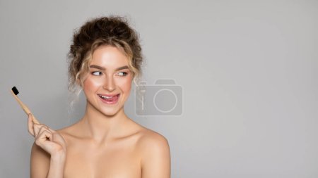 Téléchargez les photos : Pretty young woman holding toothbrush for dental wellness for teeth whitening, protection and oral hygiene on grey background, free space, panorama - en image libre de droit