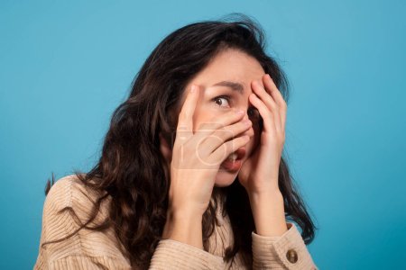 Téléchargez les photos : Frightened shocked pretty millennial european female student covering her face with hands isolated on blue background, studio, close up. Reaction to bad news, emotions of horror, fear, ad and offer - en image libre de droit
