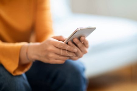 Photo for Closeup Shot Of Unrecognizable Woman Using Mobile Phone At Home, Young Female Sitting On Couch And Typing On Smartphone, Browsing Modern App On Cellphone Or Shopping Online, Cropped Shot - Royalty Free Image