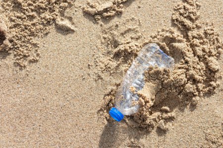 Foto de Environmental pollution. Human waste throwing away junk bottle on the sand, bring the sea to rot, closeup. Beach garbage environmental damage causing global warming - Imagen libre de derechos