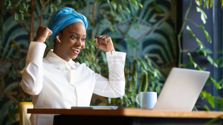 Photo for Business startup. Happy emotional young african american woman in smart casual sitting at table, looking at laptop screen and gesturing, celebrating success, cafe interior, panorama with copy space - Royalty Free Image