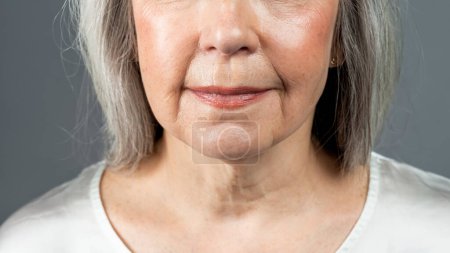 Photo for Lips of smiling old european woman with gray hair, isolated on gray background, studio, cropped, close up. Skin and beauty care, spa treatments, age-related changes procedure, ad and offer, panorama - Royalty Free Image