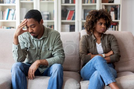 Téléchargez les photos : Unhappy millennial black couple in casual outfits sittng on sofa at therapist office, husband and wife feeling down after quarrel, spouses thinking about divorce, attend family counseling, copy space - en image libre de droit