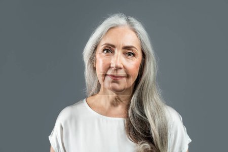 Photo for Smiling old european female with gray hair looking at camera, isolated on gray background, studio, empty space. Wrinkle treatment, skin and beauty care, cosmetology, anti-aging procedure, ad and offer - Royalty Free Image