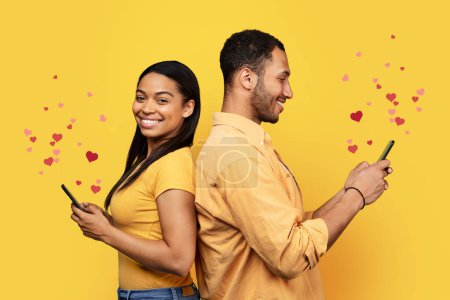 Photo for Cheerful young african american guy and female back to back, chatting on phones with hearts, isolated on yellow background, collage, studio. Relationship, love, app for social networks, ad and offer - Royalty Free Image