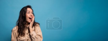 Photo for Cheerful excited shocked millennial european lady student with open mouth looking at empty space, isolated on blue background, studio, panorama. Reaction to surprise, good news emotions, ad and offer - Royalty Free Image
