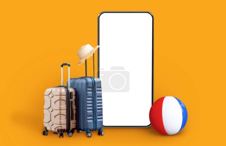 Téléchargez les photos : Two luggages small and medium size modern plastic travel bags, beach ball and big smartphone with white blank screen with wicker hat on, orange studio background, mockup, collage. Travelling, tourism - en image libre de droit