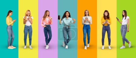 Téléchargez les photos : Glad young diverse women in casual typing on smartphone show phone with empty screen, isolated on blue background, studio, panorama. Lifestyle, online communication, technology, app recommendation - en image libre de droit