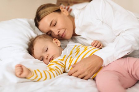 Photo for Peaceful mother and cute little child girl lying on bed, sleeping together with tranquility, mom embracing daughter during daytime sleep. Mother protection concept - Royalty Free Image