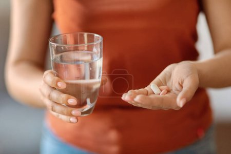 Téléchargez les photos : Young Female Holding Pile Of Pills And Glass Of Water In Hands, Closeup Shot Of Unrecognizable Woman Taking Prescribed Medicine Or Vitamin Supplements For Beauty And Health, Cropped Image - en image libre de droit