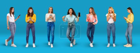 Foto de Cheerful young international women in casual typing on smartphone, show phone with blank screen, isolated on blue background, studio, panorama. Victory, lifestyle, online communication and new app - Imagen libre de derechos