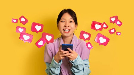 Photo for Cheerful surprised young chinese female has romantic chat with hearts on phone isolated on yellow studio background, panorama, collage. Relationships and love, app for dating remotely, social media - Royalty Free Image