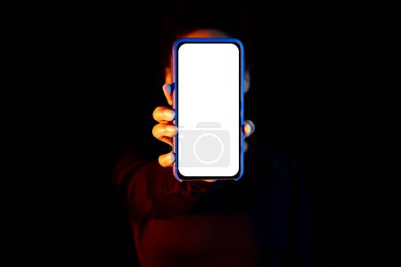 Photo for Mockup for app or website. Woman showing smartphone with white blank screen over black background with neon lights, free copy space - Royalty Free Image
