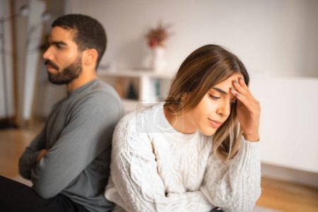 Despaired offended millennial european woman ignores arab male after quarrel, think about divorce and breakup in room interior. Problems in love relationships at home, conflict, stress and bad news