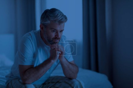 Téléchargez les photos : Stressé bouleversé réfléchi beau barbu européen mature homme en pyjama assis sur le lit la nuit, éveillé de mauvaises pensées, éprouvant des difficultés dans la vie, intérieur de la maison, espace de copie - en image libre de droit