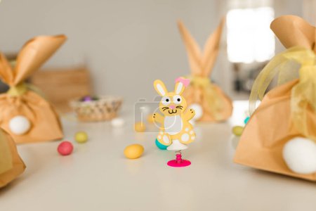 Photo for Closeup Shot Of Easter Decoration Standing On Table At Home, Creative Festive Background With Cute Bunny Toy, Chocolate Egs And Handmade Craft Paper Bags, Selective Focus On Rabbit - Royalty Free Image