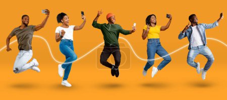 Photo for Cheerful emotional young african american people in casual jumping, make selfie on phone, enjoy victory, isolated on orange background, studio, panorama. Lifestyle online, social media, tech and app - Royalty Free Image