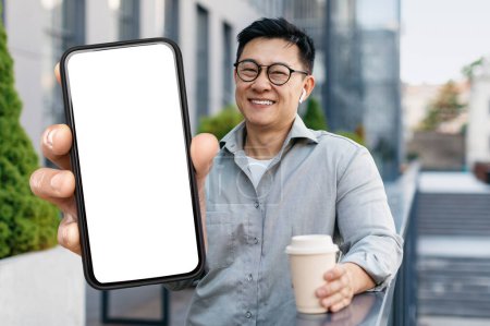 Photo for Smiling Asian Man Holding Takeaway Coffee Outdoors And Showing Big Blank Smartphone, Happy Middle Aged Chinese Male Wearing Glasses Advertising Online Offer Or New Mobile App, Collage, Mockup - Royalty Free Image